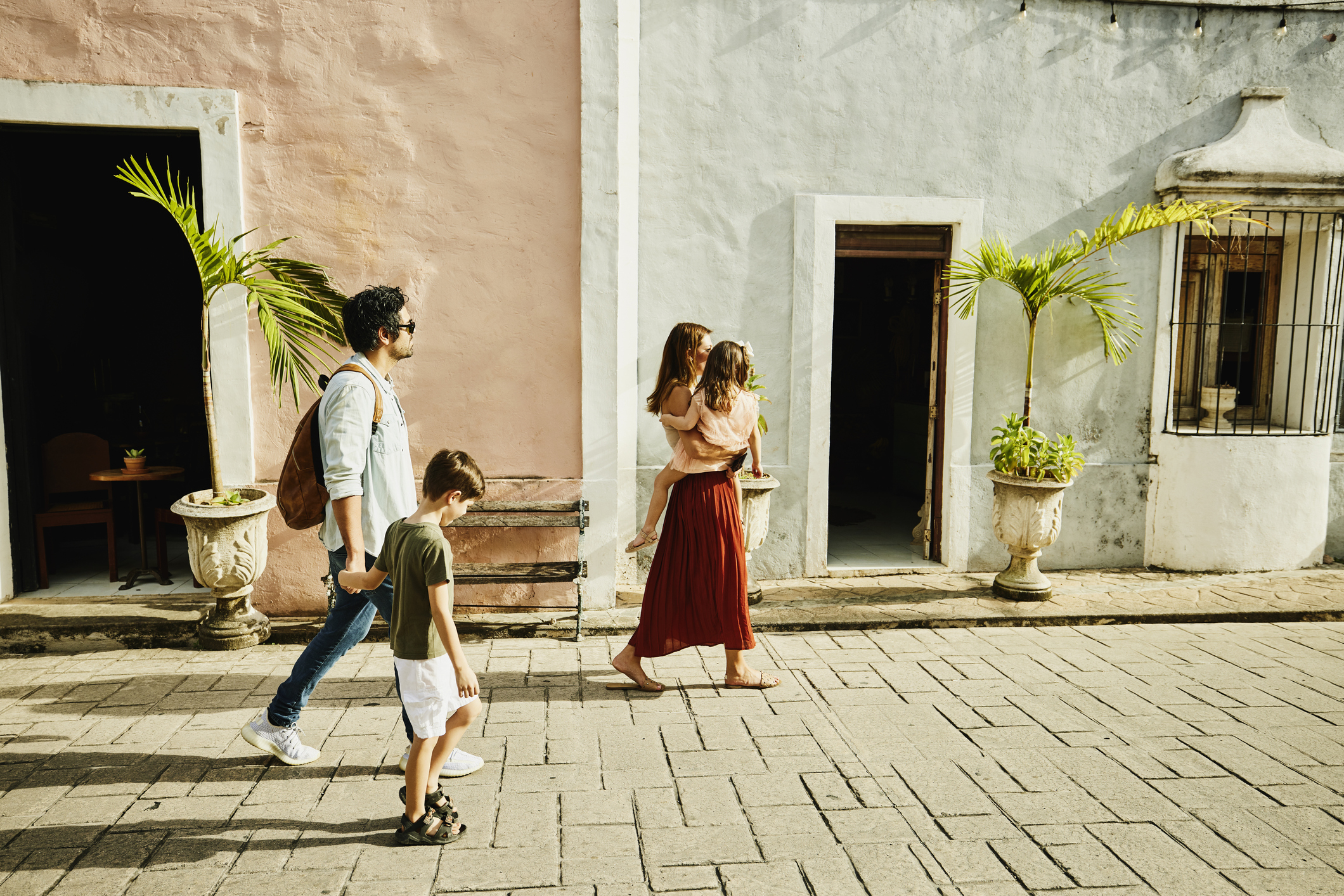 Wide shot of family walking down street while exploring town during vacation