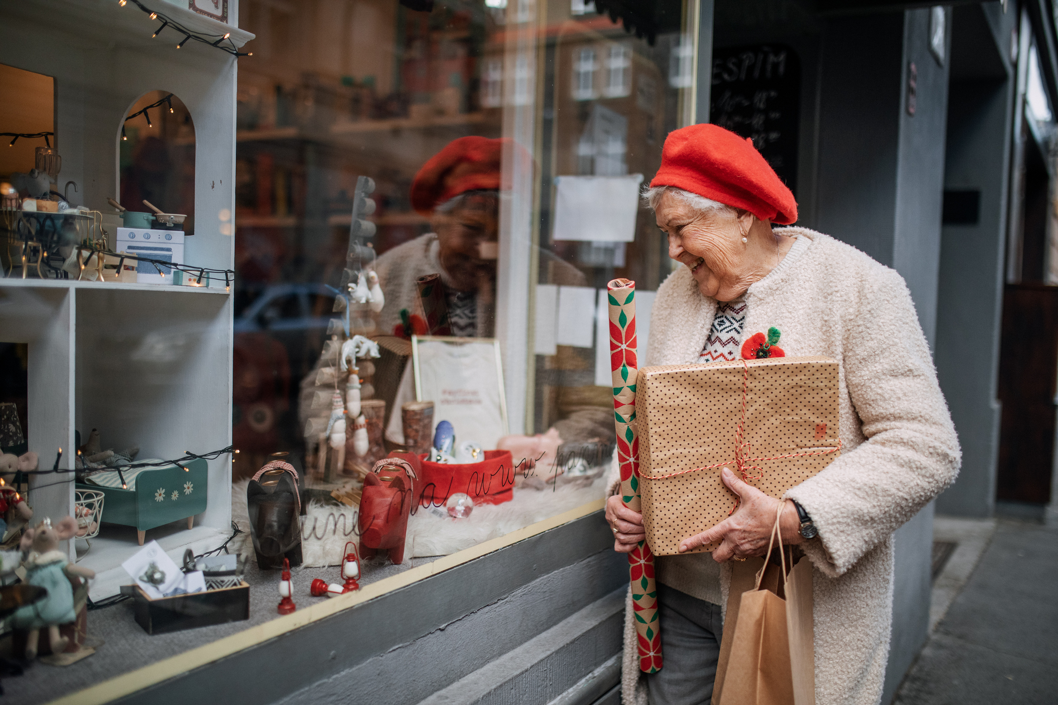 Senior woman shopping Christmas gifts, walking in the street and looking in shop showcase.