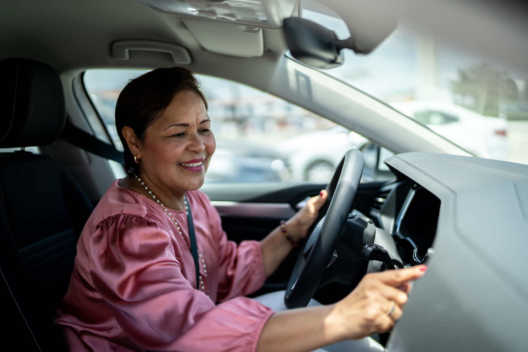 Mature woman using car GPS navigation or changing radio music inside her car