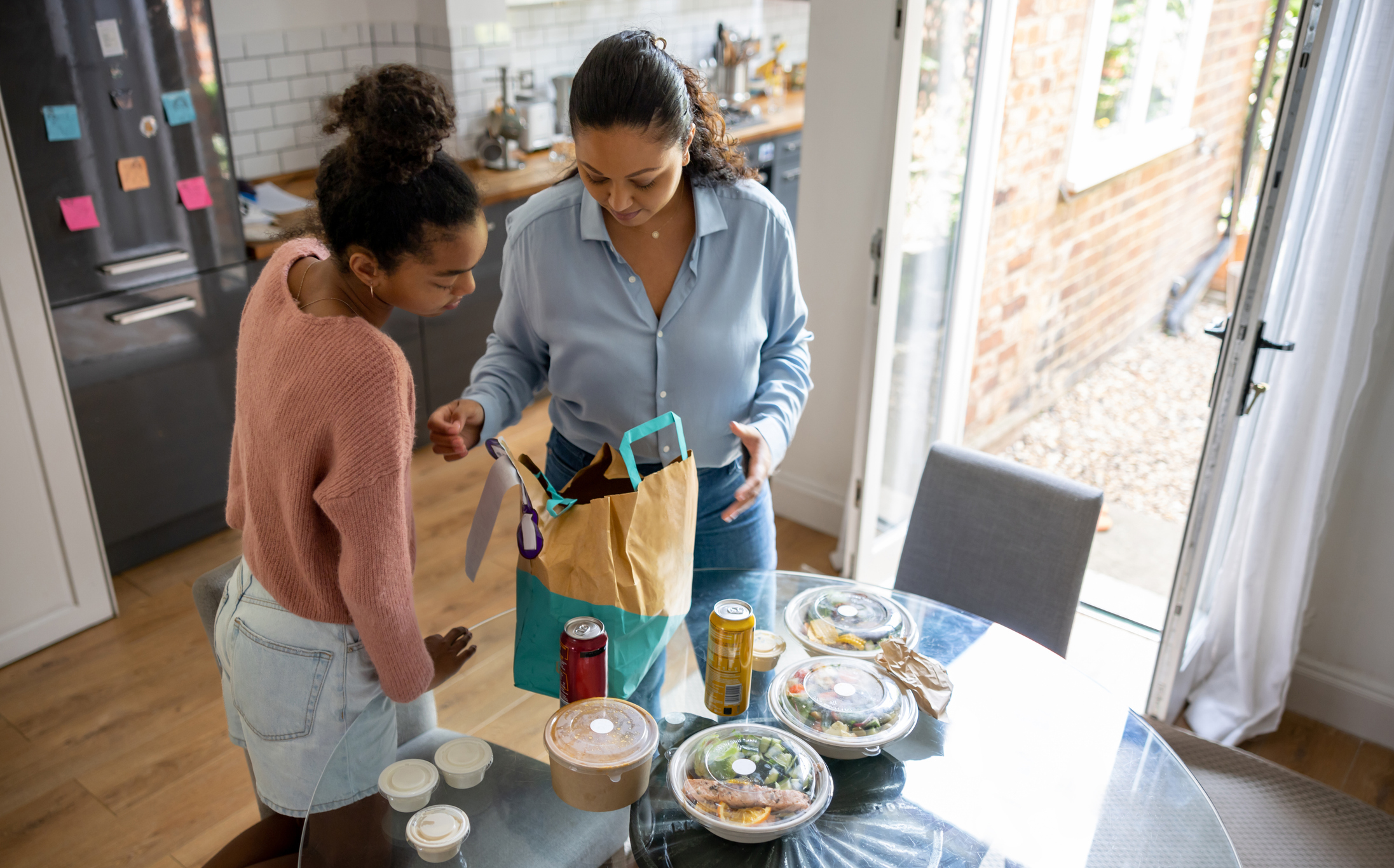 Mother and daughter eating healthy take out food at home - food delivery concepts