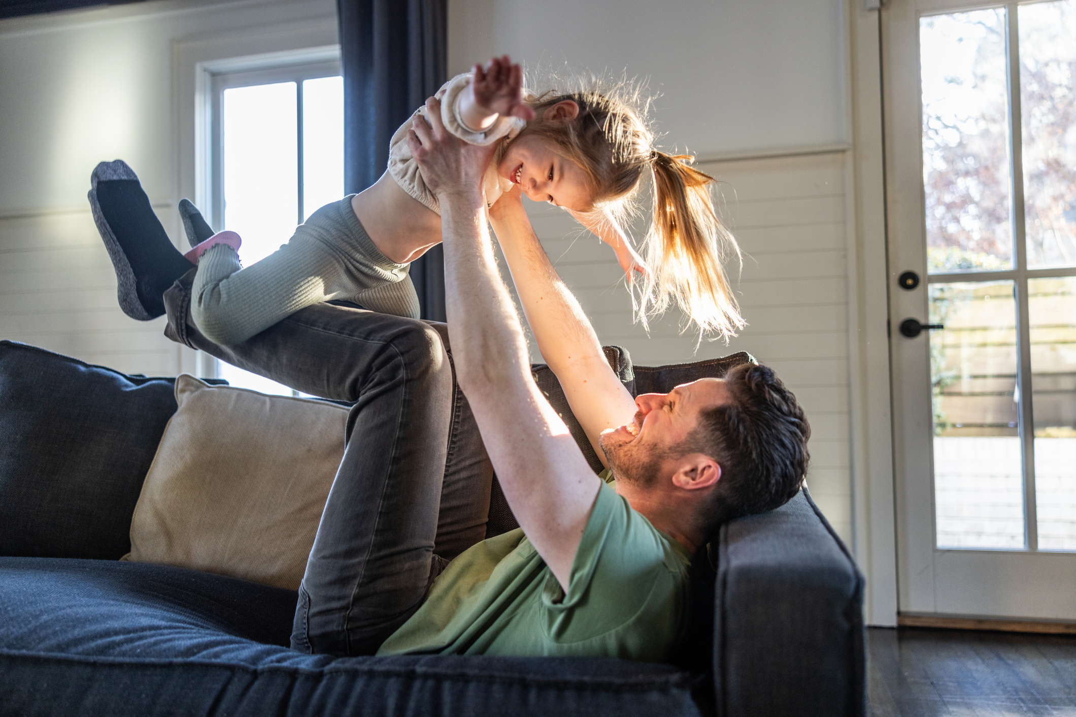 Father giving young daughter an airplane ride in living room