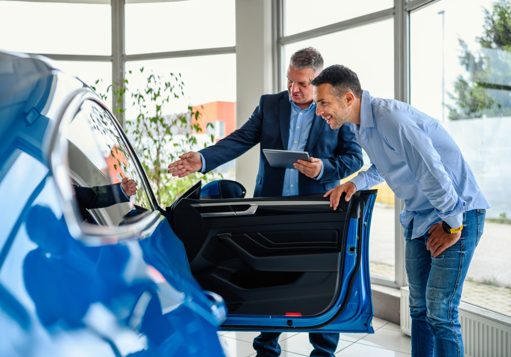 Salesman helping the male customer to choose a new car